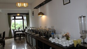Un buffet avec plusieurs points de service, un distributeur d’eau et un vase rempli de fleurs.