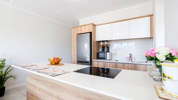 A modern kitchen with a central island, wooden cabinets, a stainless steel refrigerator, and a microwave.