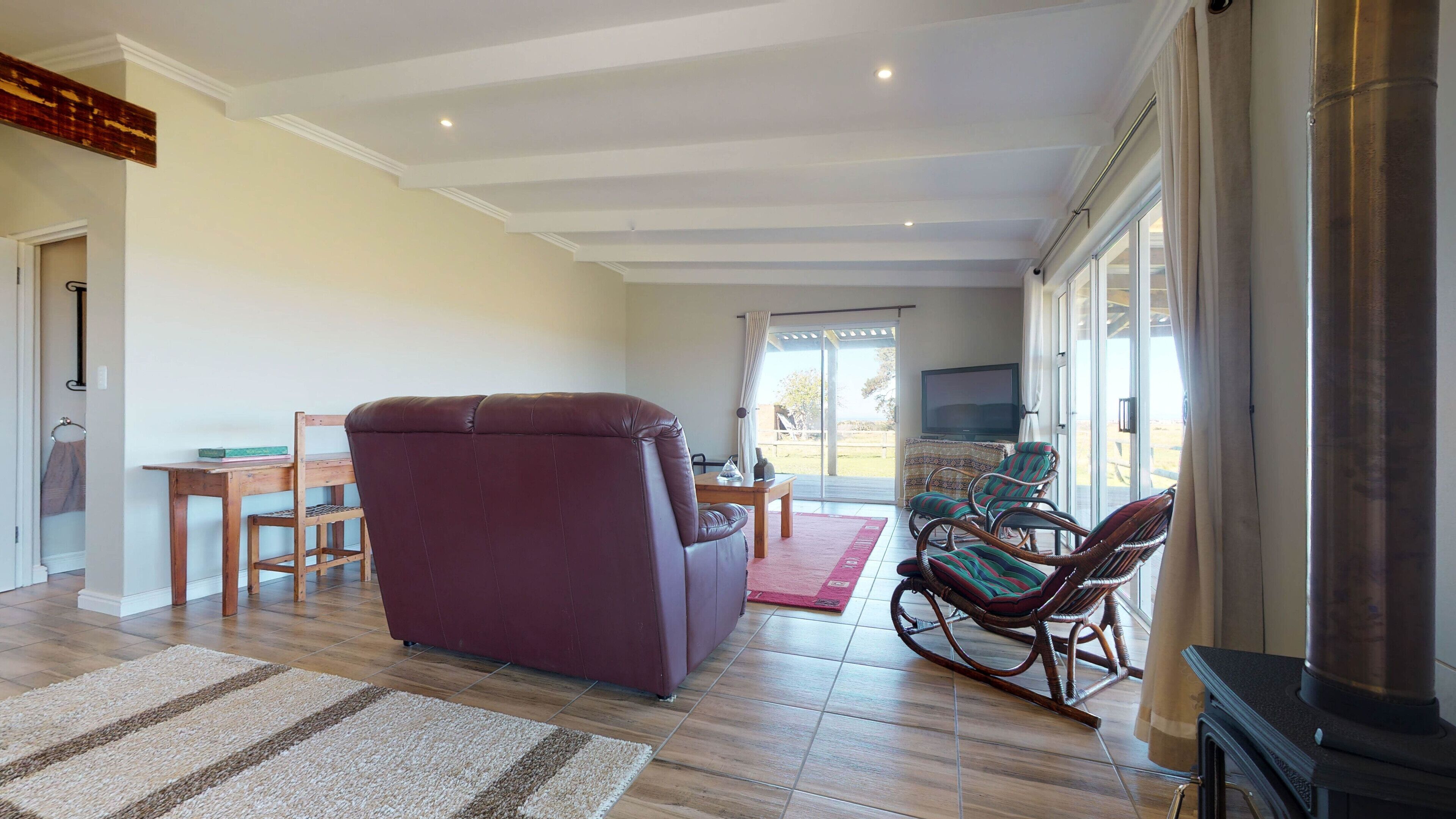A spacious living room with a leather sofa, a dining table, and a fireplace.