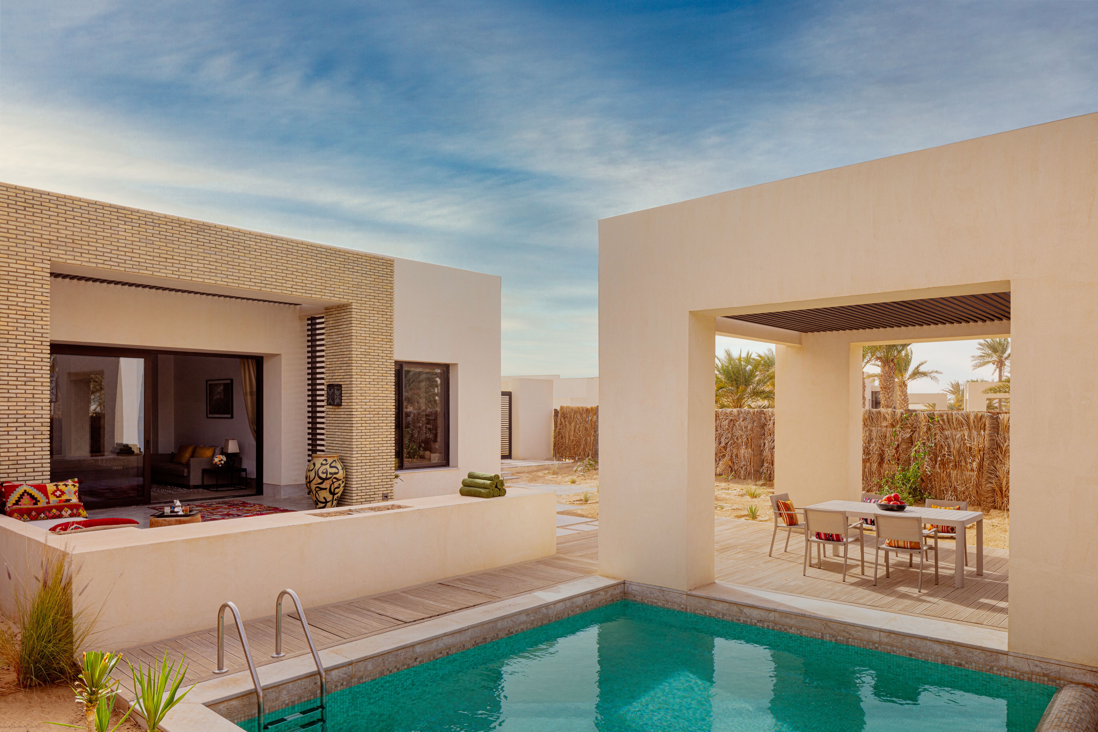 Un espace piscine extérieur moderne, doté d’une terrasse, de coins salon et offrant une vue sur le paysage environnant.
