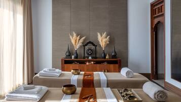 Un cuarto de spa con dos camillas de masaje, toallas, un aparador de madera y objetos decorativos.