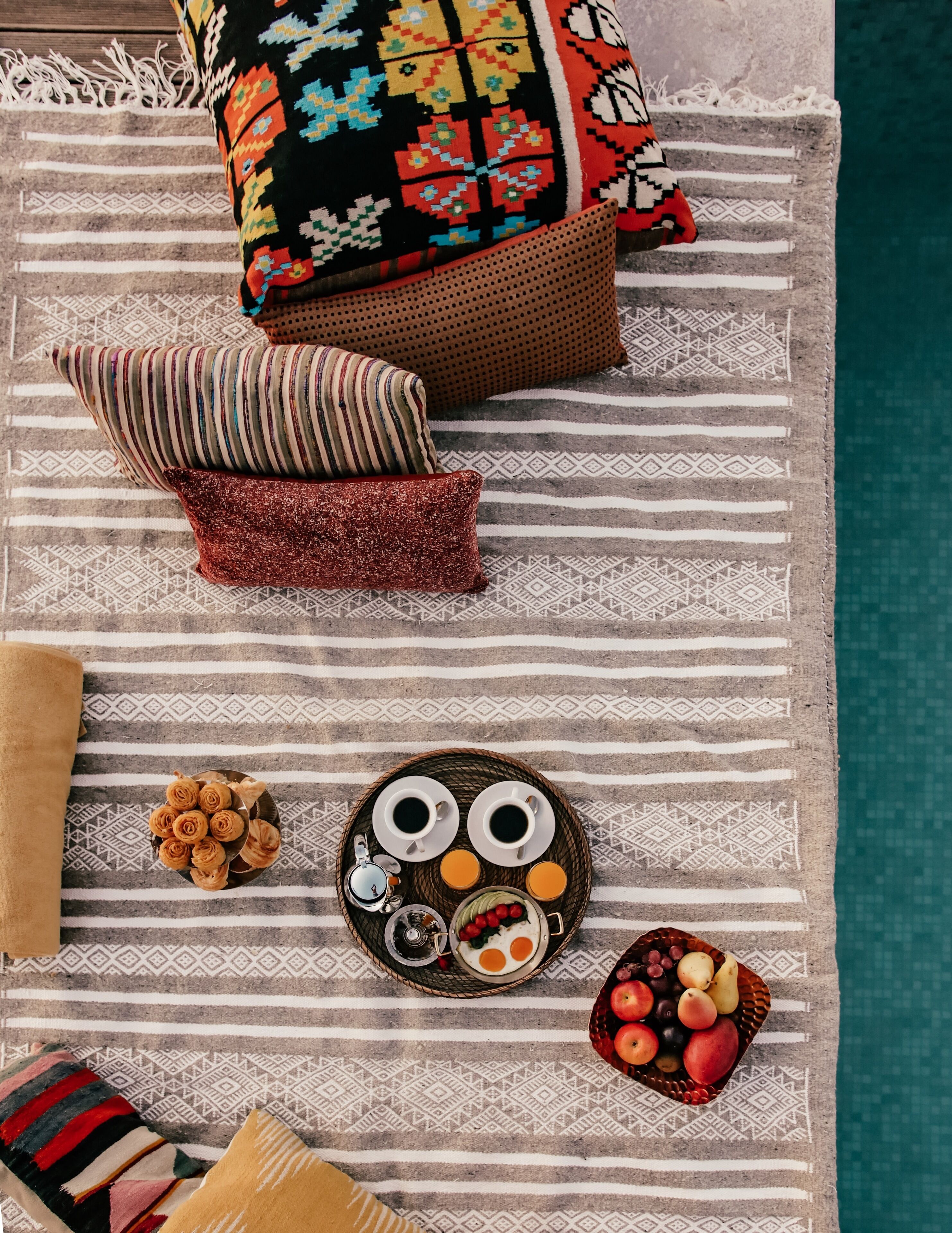 A neatly arranged breakfast tray with coffee, eggs, and fruit on a patterned tablecloth.
