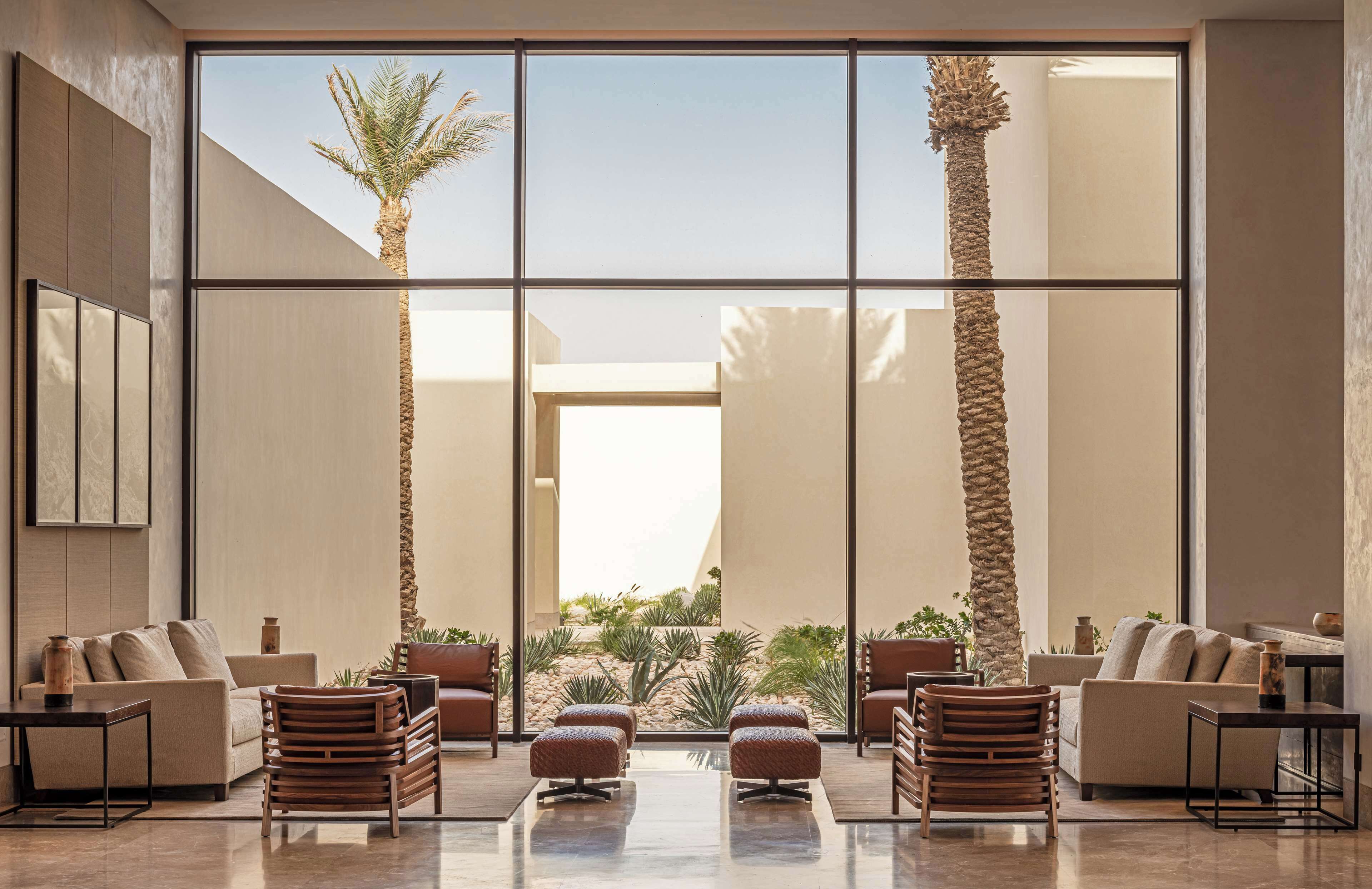 A spacious lobby with a large glass wall, modern furniture, and a view of a landscaped outdoor area.