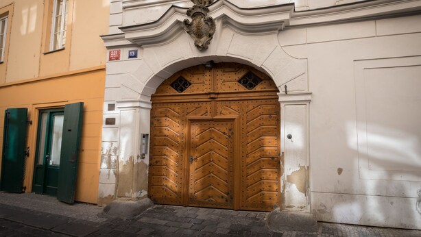 A building with a large wooden door, a green door to the left, and a plaque above the door. - Hidden gem in heart of Prague (Prague)