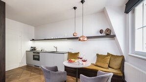 A modern kitchen with a dining area, featuring a round table, two chairs, a sofa, pendant lights, and a built-in oven. - Hidden gem in heart of Prague (Prague)