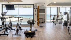 Een sportschool met cardioapparatuur, krachttoestellen en een televisiescherm met de tekst 'TV 2'.