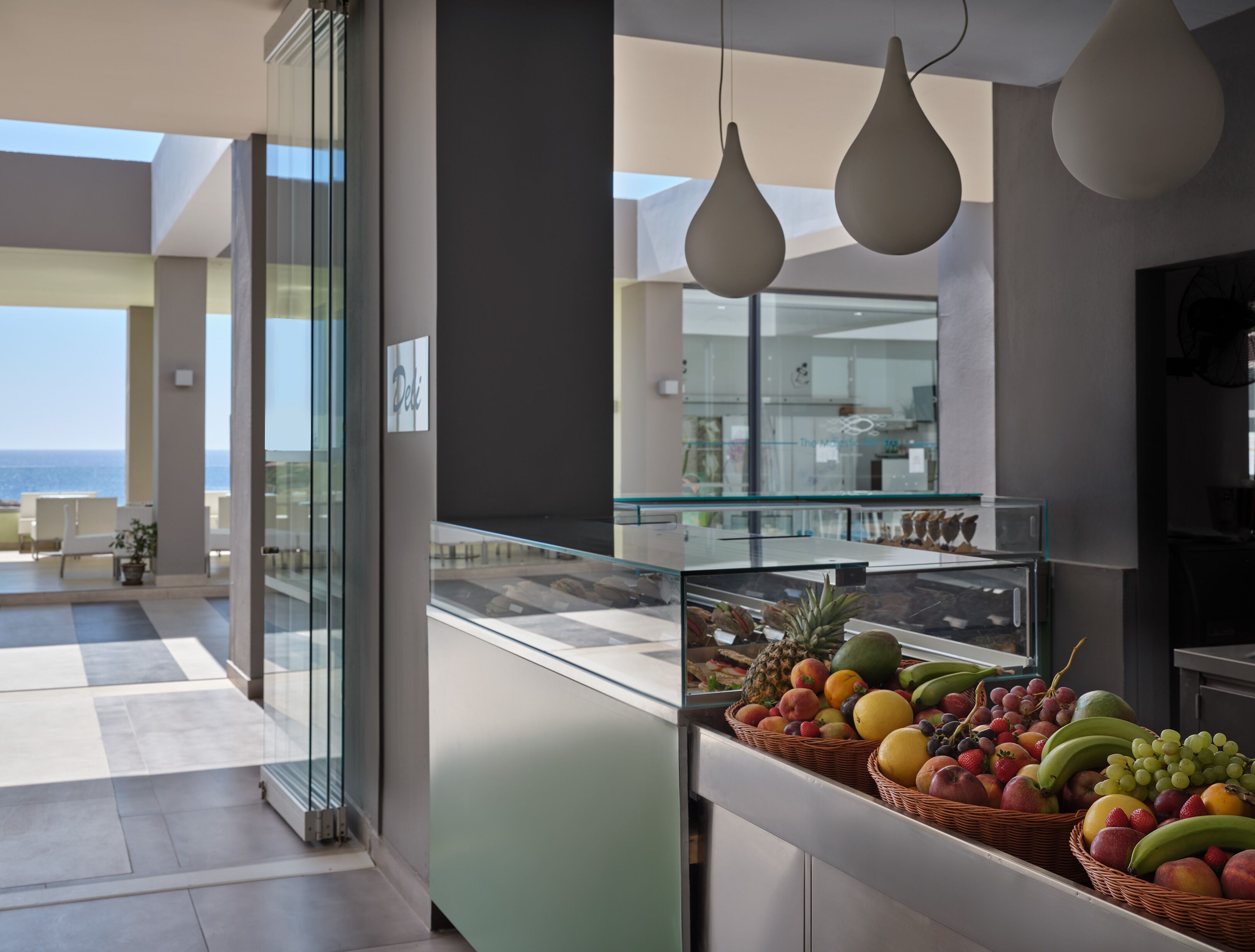 A modern kitchen with a fruit display and a view of the sea.