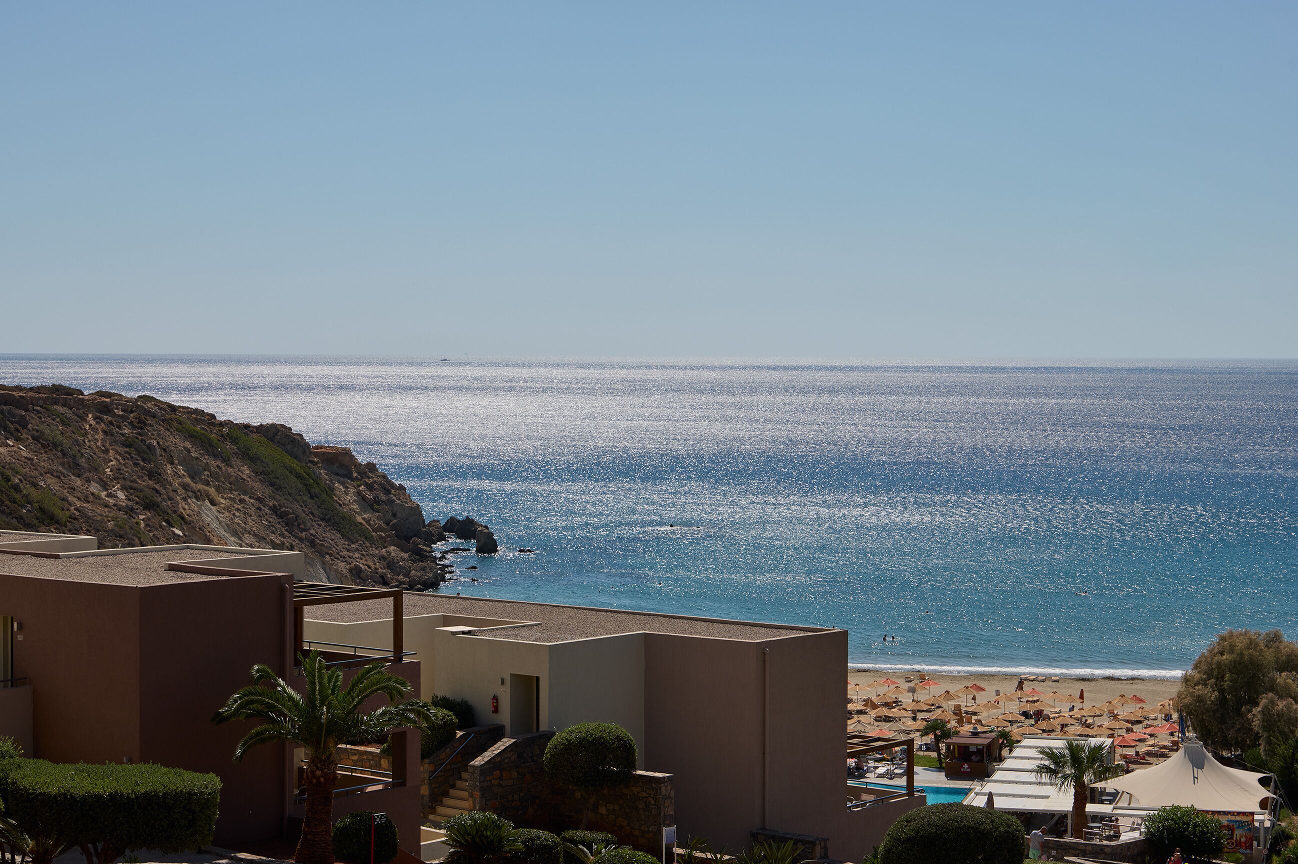 Un hotel costero con vistas al mar, una piscina y una zona de playa.