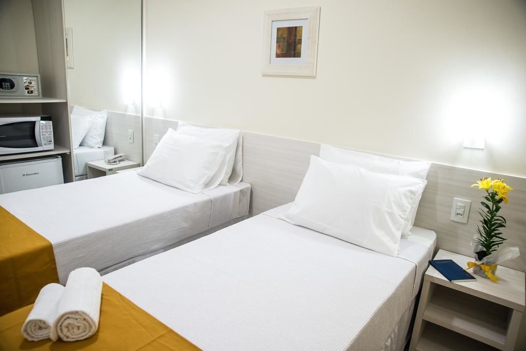 Habitación de hotel con dos camas, microondas, teléfono y una mesita con toallas.
