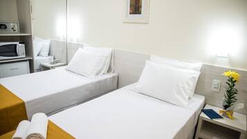 Quarto de hotel com duas camas, micro-ondas, telefone e uma pequena mesa com toalhas.