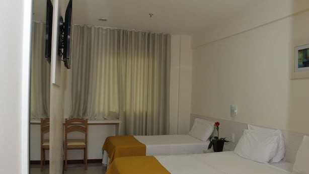 Une chambre d’hôtel avec deux lits, un bureau, une chaise et une plante en pot.
