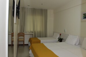 Habitación de hotel con dos camas, un escritorio, una silla y una planta en maceta.