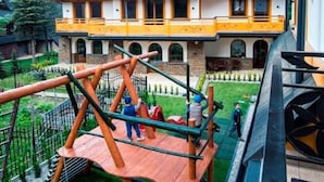 A large two-story house with a balcony and a wooden play structure in the yard.