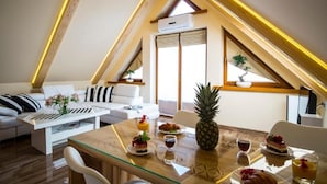 A modern loft apartment with a sloped ceiling, a dining area with a glass table, and a cozy seating arrangement.