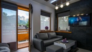 A modern living room with a grey sofa, a coffee table, and a TV mounted on the wall.