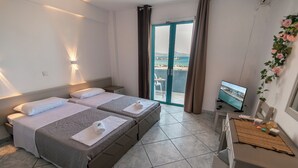 A hotel room with two beds, a TV, and a balcony with a view of the sea. - Angela & Thalia Apartments (Kos)