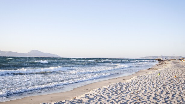 A beach with waves, a clear sky, and distant mountains. - Angela & Thalia Apartments (Kos)