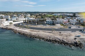 A coastal town with residential buildings, a curved road, and a rocky shoreline. - Angela & Thalia Apartments (Kos)