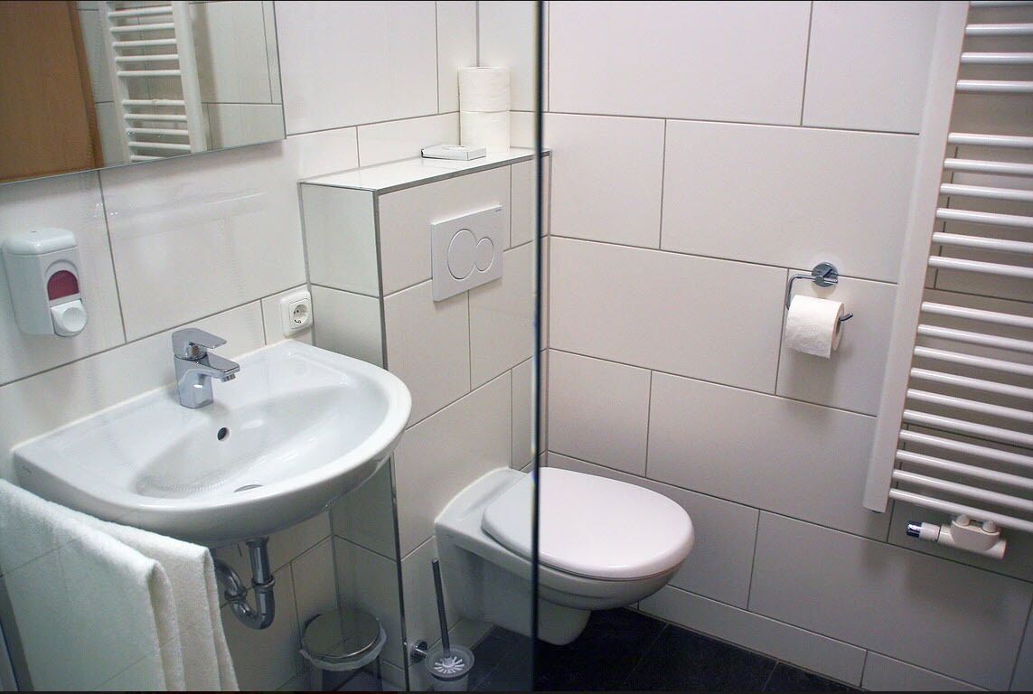 Une salle de bain avec un lavabo blanc, des toilettes et un porte-serviettes.