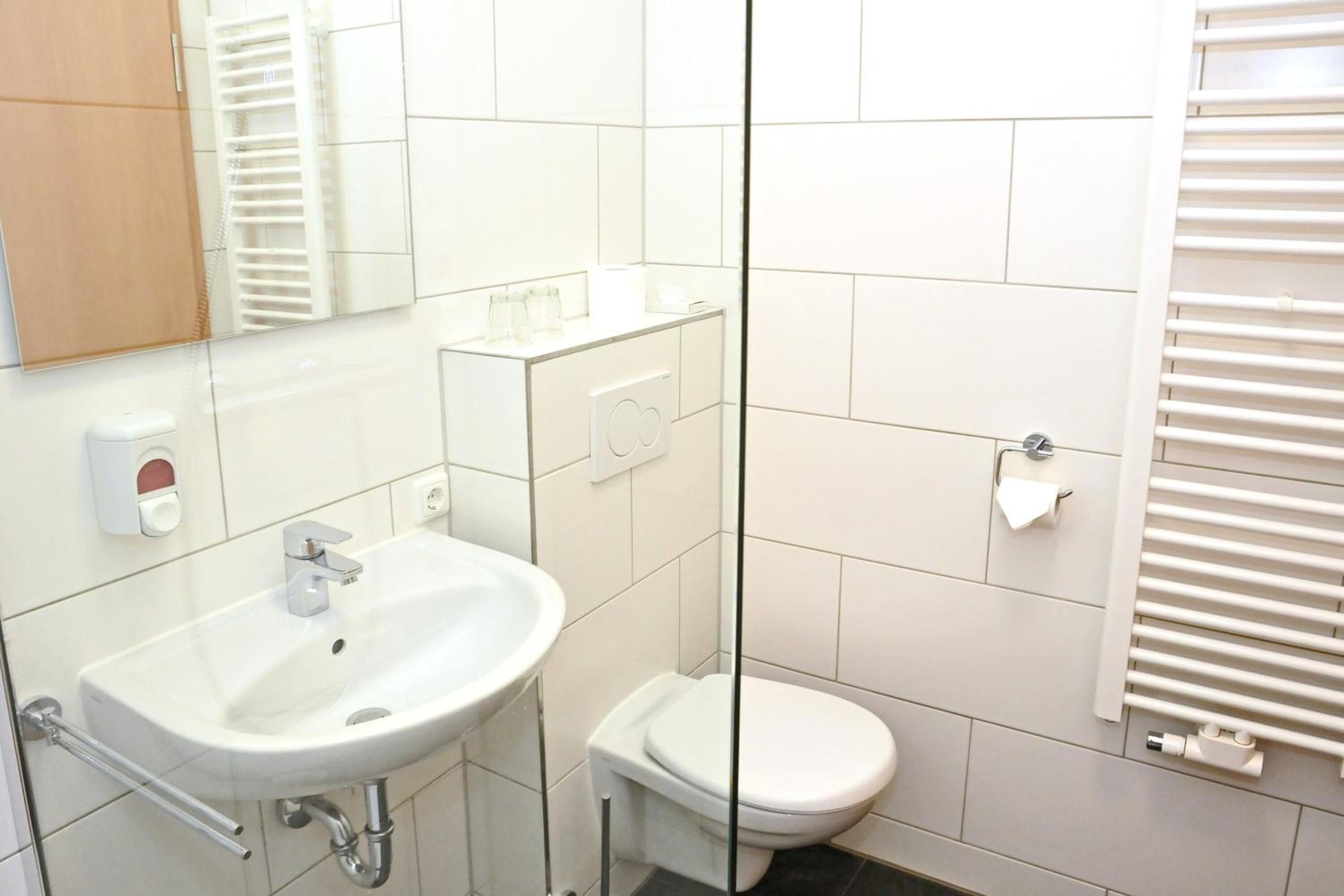 Un baño moderno con lavamanos, inodoro y toallero blancos.