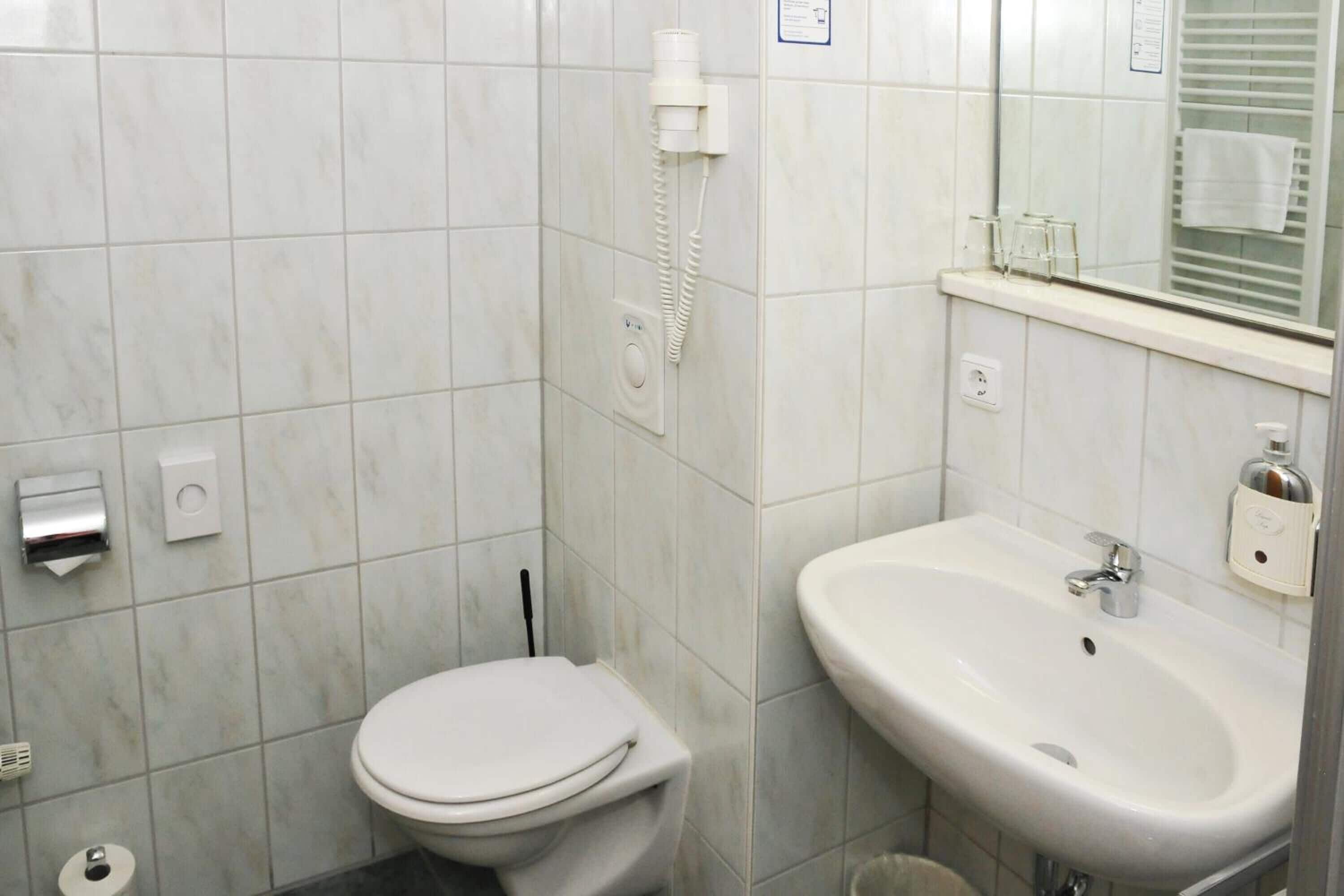 A bathroom with a toilet, sink, and a mirror.