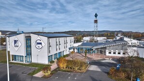A hotel with a 24-hour check-in service, a visible tower, and a parking area.