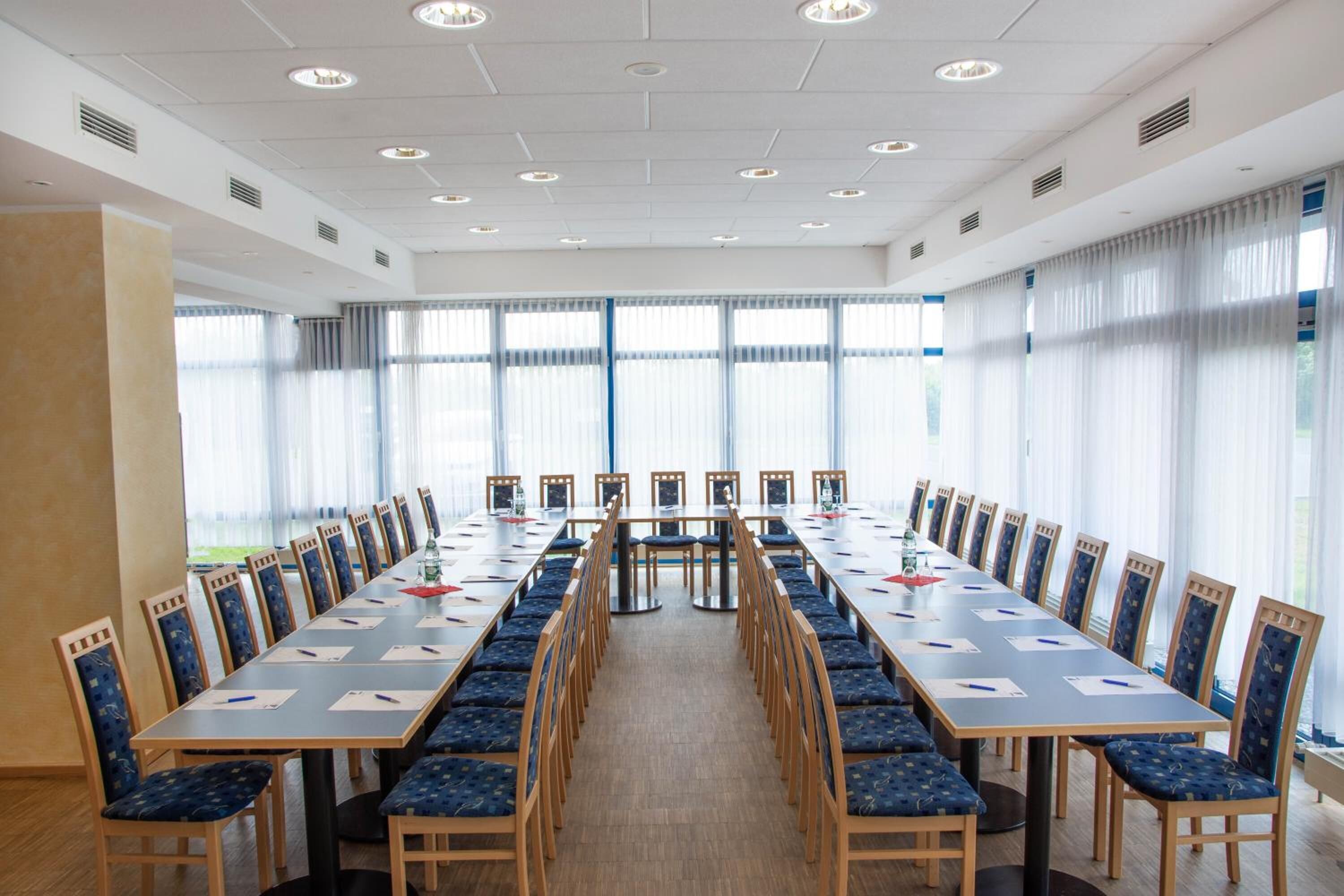Een vergaderruimte met een lange tafel, stoelen en grote ramen.