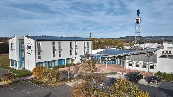 A hotel with a modern design, a parking lot, and a view of the surrounding area. - Miratel Hotel (Mitterteich)