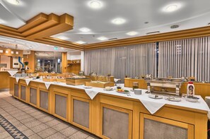 A buffet setup with multiple serving stations, a reception area, and a large window with curtains. - Miratel Hotel (Mitterteich)