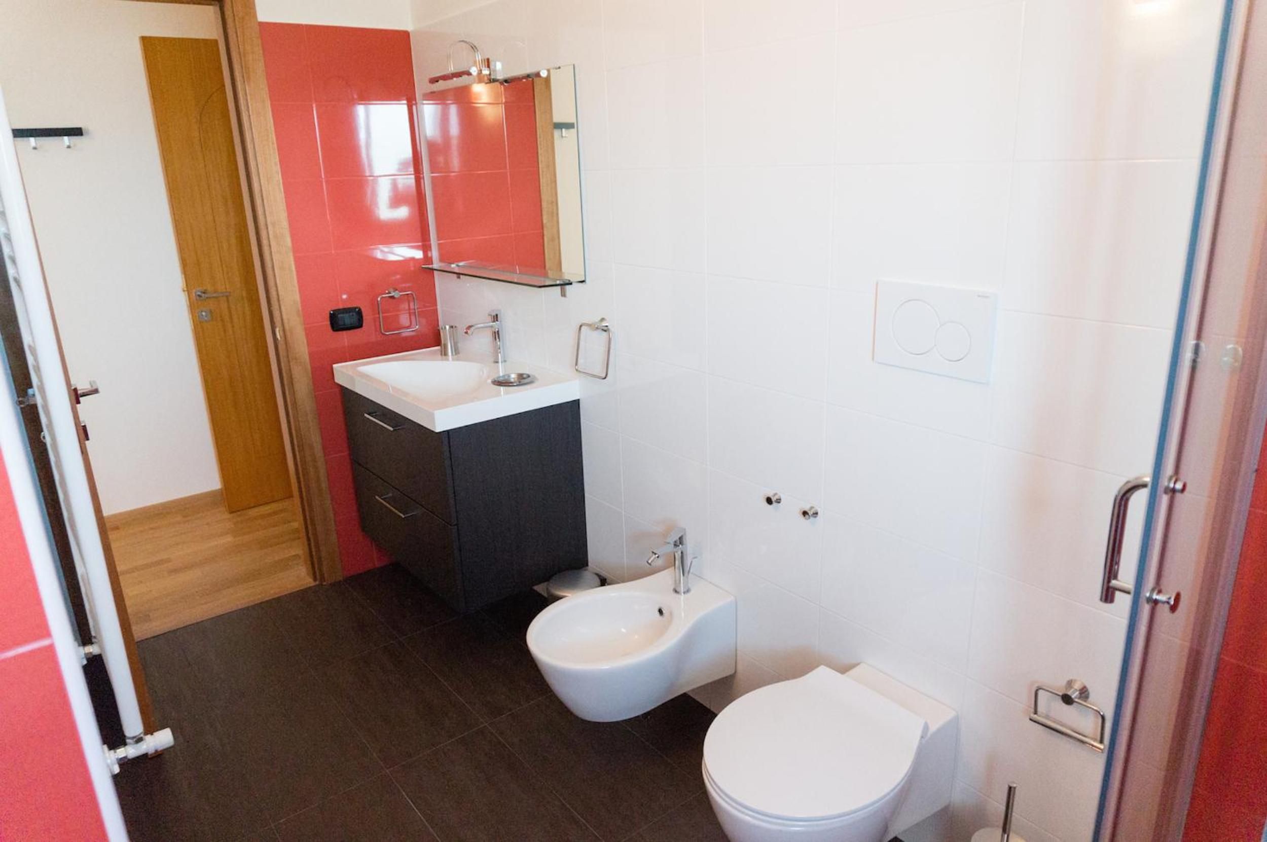 Un baño moderno con un lavamanos blanco, un bidé y un inodoro.