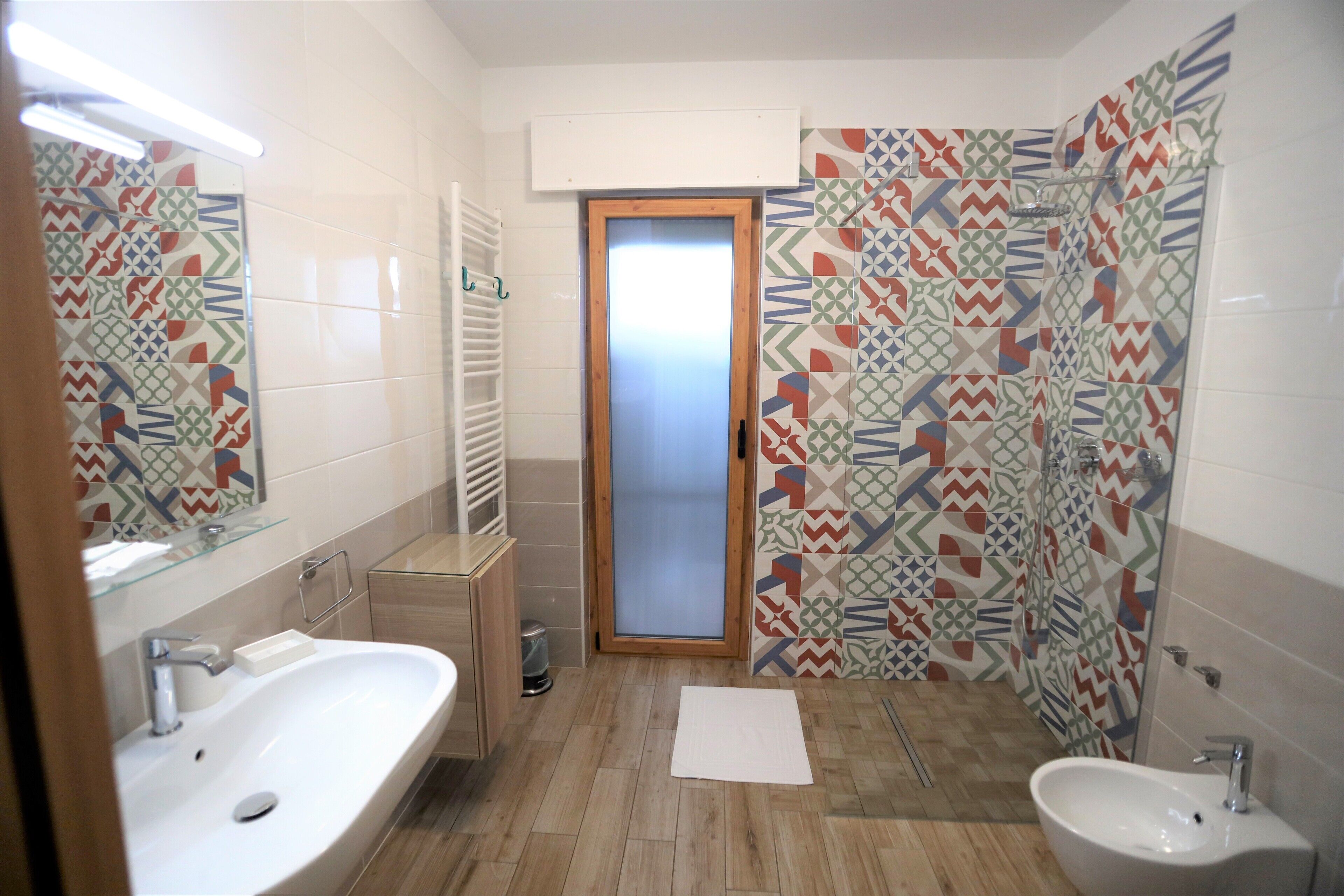 A bathroom with two sinks, a shower, and patterned tiles.
