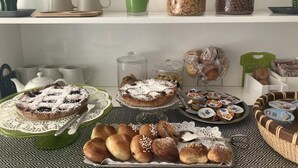 Een ontbijtbuffet met diverse gebakjes, broodsoorten en drankjes.