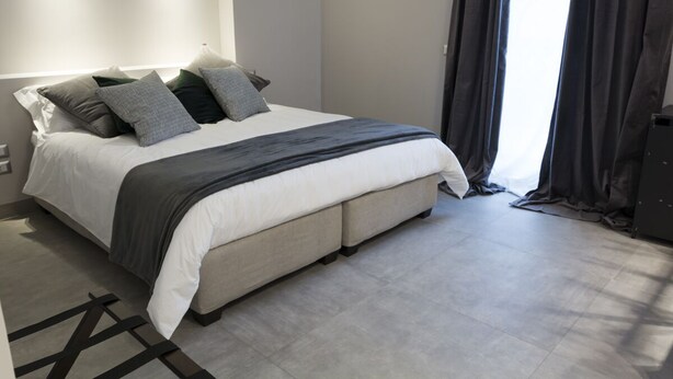 Een moderne slaapkamer met een groot bed, een nachtkastje en een raam met gordijnen.