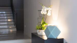 Een trap die uitkomt op een plateau met een potplant en een geometrisch lamparmatuur op een zwart console.