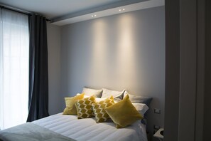 Ein modernes Schlafzimmer mit einem großen Bett, grauen Wänden und einem Fenster mit Vorhängen.