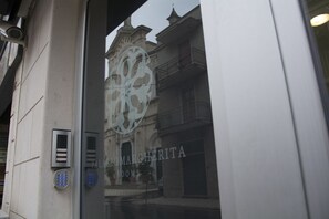 Eine Gebäudefassade mit einem großen Fenster, das ein Logo und den Schriftzug "PALAZZO MARGHERITA ROOMS" zeigt.