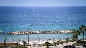 A coastal view with a rocky breakwater, beach, and a clear blue sea. - Modern Gem with Stunning Balcony by Sea N Rent (Herzliya)