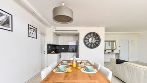 A modern dining area with a wooden table, light blue plates, and a large wall clock. - Modern Gem with Stunning Balcony by Sea N Rent (Herzliya)