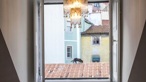 Zona pranzo con tavolo apparecchiato per due, un lampadario e una finestra con vista sugli edifici.