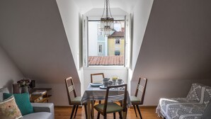 Una camera da letto mansardata accogliente con zona pranzo, divano e vista sulla città.