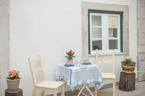 Enjoy a romantic meal for two in this charming outdoor seating area, complete with a table, chairs, and a beautiful potted plant.
