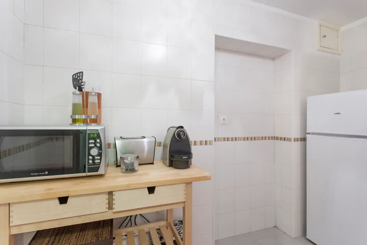 Eine kleine Küche mit einer Mikrowelle, einem Toaster und einer Kaffeemaschine auf einem Holztisch.