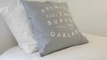 Una cama con dos almohadas, una blanca y otra gris con texto.