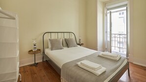 Une chambre à coucher avec un lit, une table de chevet, une lampe et une vue sur l’extérieur.