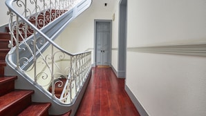 Un escalier en bois, agrémenté de rampes en métal ouvragé, mène à une porte.