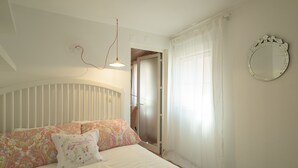 Ein Schlafzimmer mit einem Bett, einem Schminkspiegel und einer Tür zu einem weiteren Raum.