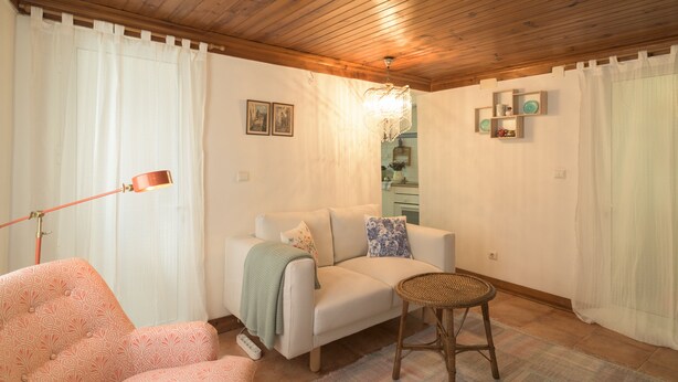 Ein gemütliches Wohnzimmer mit Holzboden, einer Couch mit Kissen, einem Beistelltisch und einer Stehlampe.