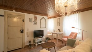 Ein gemütliches Wohnzimmer mit Fernseher, Esstisch, Sofa und Sessel.