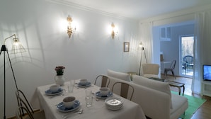 Un comedor con una mesa preparada para cuatro personas, un sofá y un televisor al fondo.