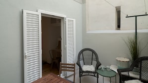 Un pequeño espacio al aire libre con sillas de mimbre, una mesa y una planta en maceta.